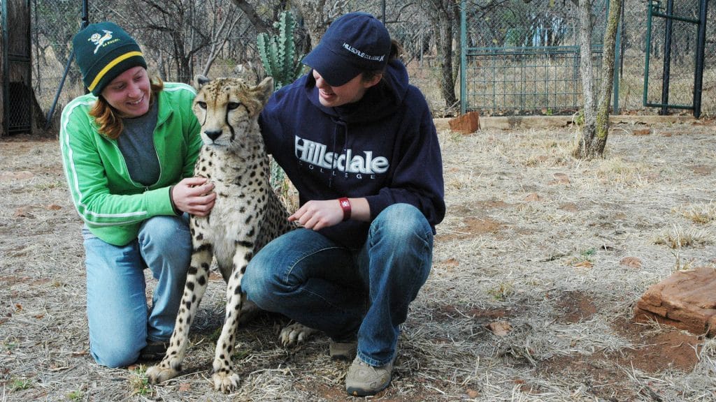 Two students posing with a cheetah.