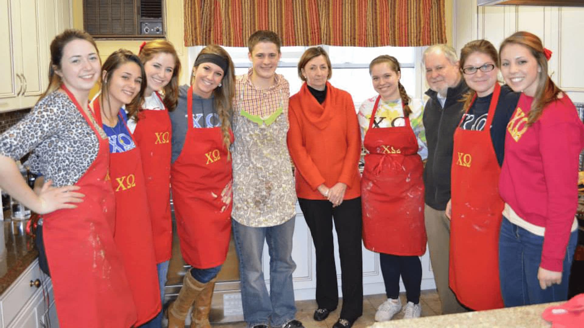 Chi Omega group photo in baking aprons with Dr. and Mrs. Arnn.