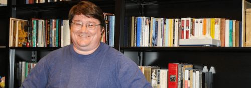Dr. David Stewart in front of bookshelves.