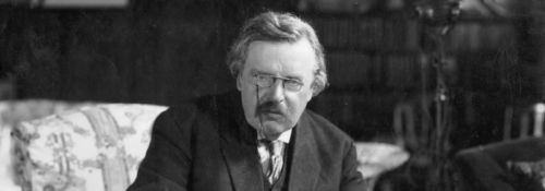 G. K. Chesterton writing at his desk.