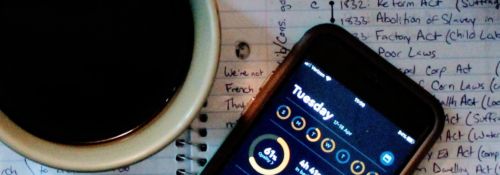 Photo of a coffee cup and phone with sleep app open, sitting on a page of student's notes