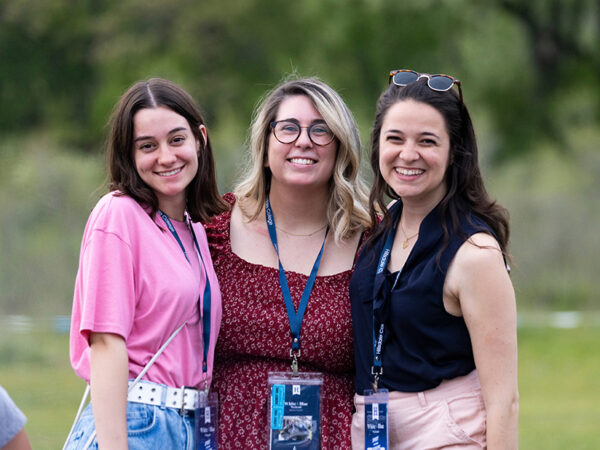 Three female alumni smile and pose for a picture.